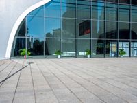 a large modern building is reflected by large glass windows and trees in the background's silhouette