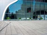 a large modern building is reflected by large glass windows and trees in the background's silhouette