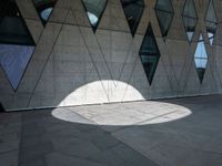 the shadow of a white umbrella on the side of a building that is covered in windows