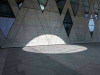 the shadow of a white umbrella on the side of a building that is covered in windows