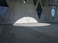 the shadow of a white umbrella on the side of a building that is covered in windows