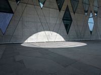 the shadow of a white umbrella on the side of a building that is covered in windows