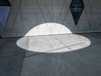 the shadow of a white umbrella on the side of a building that is covered in windows