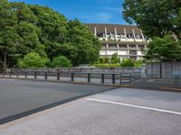 a view of a stadium from the street, showing many trees and bushes in the distance