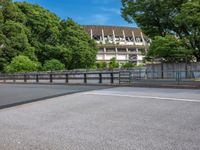 a view of a stadium from the street, showing many trees and bushes in the distance