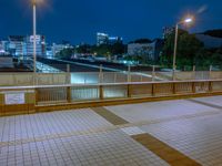 people standing on a subway platform with many buildings in the background at night light in tokyo