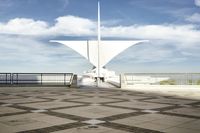 a white sculpture sitting in the middle of a tiled area under blue skies with a sky background