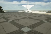 a white sculpture sitting in the middle of a tiled area under blue skies with a sky background