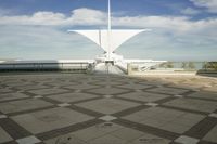 a white sculpture sitting in the middle of a tiled area under blue skies with a sky background