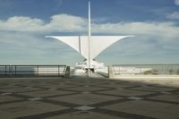 a white sculpture sitting in the middle of a tiled area under blue skies with a sky background