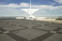 a white sculpture sitting in the middle of a tiled area under blue skies with a sky background