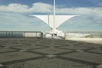 a white sculpture sitting in the middle of a tiled area under blue skies with a sky background