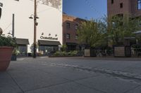 the sidewalk is empty near two planters with tables and chairs around it, and several people eating