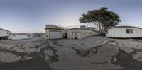 the panorama lens is shot in this fish eye image to the left is one of the buildings on the right is a small building that has white walls at the top of the building