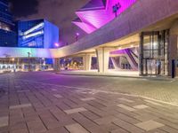 a couple of large glass buildings next to each other at night in a city area