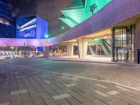 a couple of large glass buildings next to each other at night in a city area