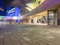 a couple of large glass buildings next to each other at night in a city area