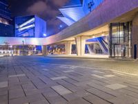 a couple of large glass buildings next to each other at night in a city area