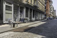 a city sidewalk that has graffiti on the side of it and several buildings in the background