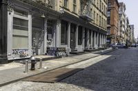 a city sidewalk that has graffiti on the side of it and several buildings in the background