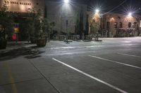 an empty parking lot at night with a parking meter in the foreground and a row of lights