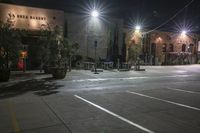 an empty parking lot at night with a parking meter in the foreground and a row of lights