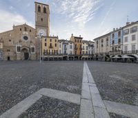 the square has many tables around it with chairs and umbrellas on the side and buildings in the distance