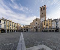 the square has many tables around it with chairs and umbrellas on the side and buildings in the distance