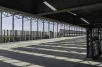 view of train station from outside of building with railings and sun shine on the ground