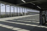 view of train station from outside of building with railings and sun shine on the ground