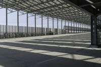 view of train station from outside of building with railings and sun shine on the ground