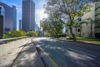 the sun is setting on an empty street that is filled with tall buildings and some trees