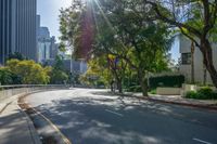 the sun is setting on an empty street that is filled with tall buildings and some trees