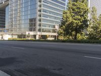 a city with tall glass buildings and traffic lights on both sides of the street with bushes in the front