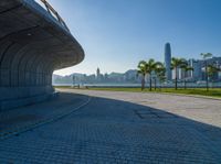 a paved road is next to a river and buildings in hong kong kong area during sunrise