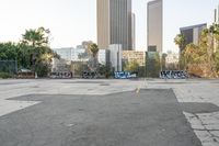 a empty parking lot in a city with city buildings in the background and graffiti all over the space