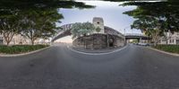 an empty street with a bridge in the background of the camera lens and the road that is wide