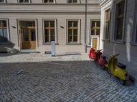 an empty parking lot with plants in the ground and on the side of the building, there is an enclosed area and windows