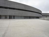 a building with cement roof near green grass and lawn in front of it, under a gray sky