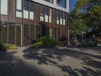 a person with a suitcase standing in front of a building near some trees and shrubs