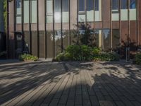 an outdoor building with lots of windows and plants on the side of the walkway near the front entrance