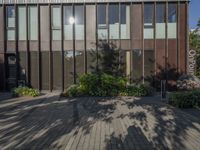 an outdoor building with lots of windows and plants on the side of the walkway near the front entrance