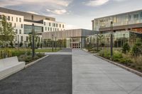 a city street surrounded by grass and tall buildings at the end of a street there is a paved pathway in front of the building