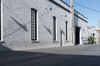 a concrete patio with windows, white brick wall, and cement walkway area next to it