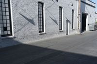 a concrete patio with windows, white brick wall, and cement walkway area next to it