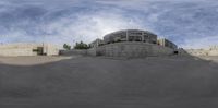 a round reflective object sits at the base of a building that stands next to a concrete road