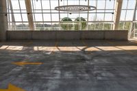 a large empty parking lot with lots of windows and arrow markings on the floor outside