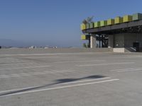 empty parking lot of commercial area with sky in background and street name sign above roof