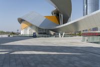 a building with a curved wall is in front of some buildings with skyscrapers behind it