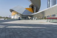 a building with a curved wall is in front of some buildings with skyscrapers behind it